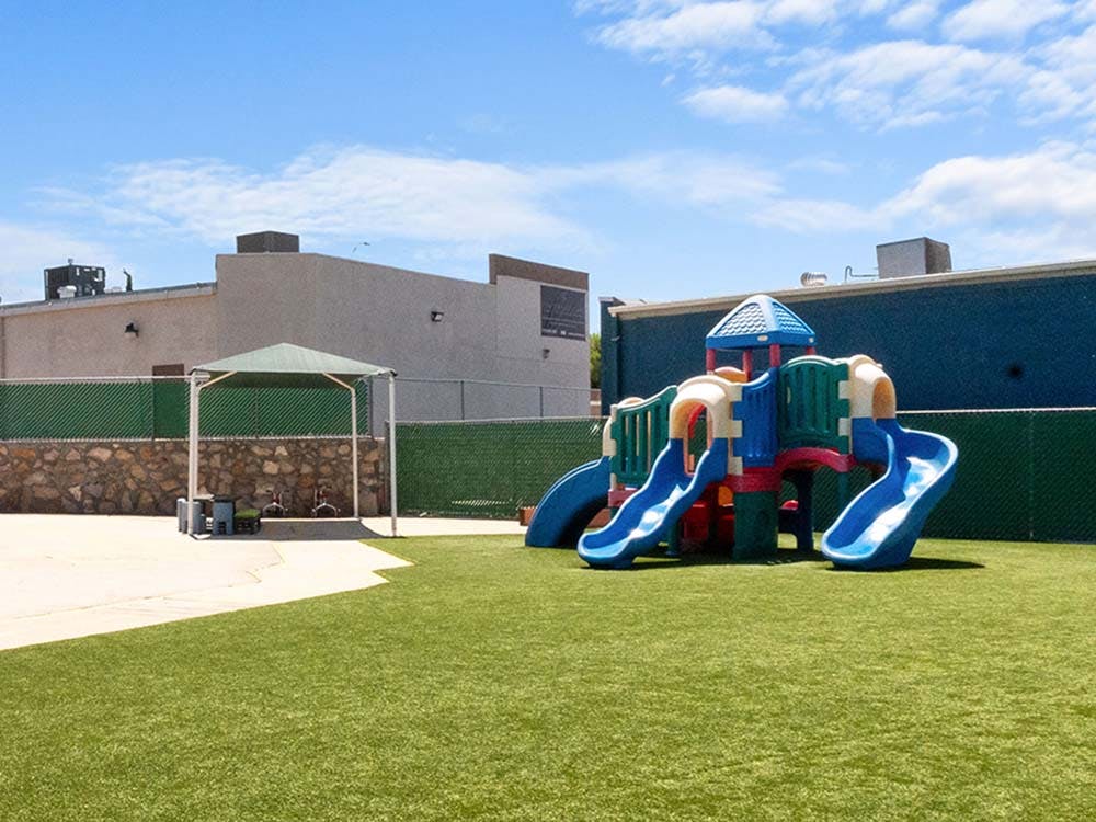 Playground with climbing structure, slides, and green turf