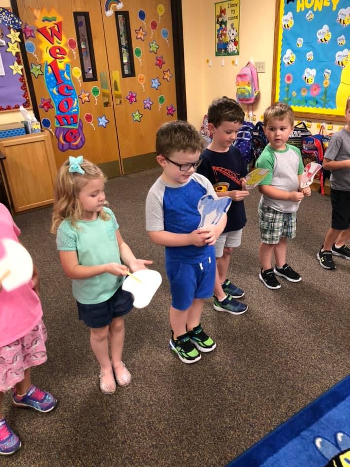 Children standing in a line holding paper cutouts