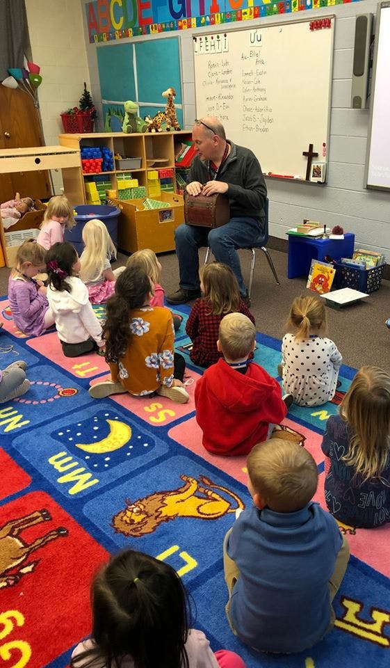 Adult playing an instrument for children in a classroom
