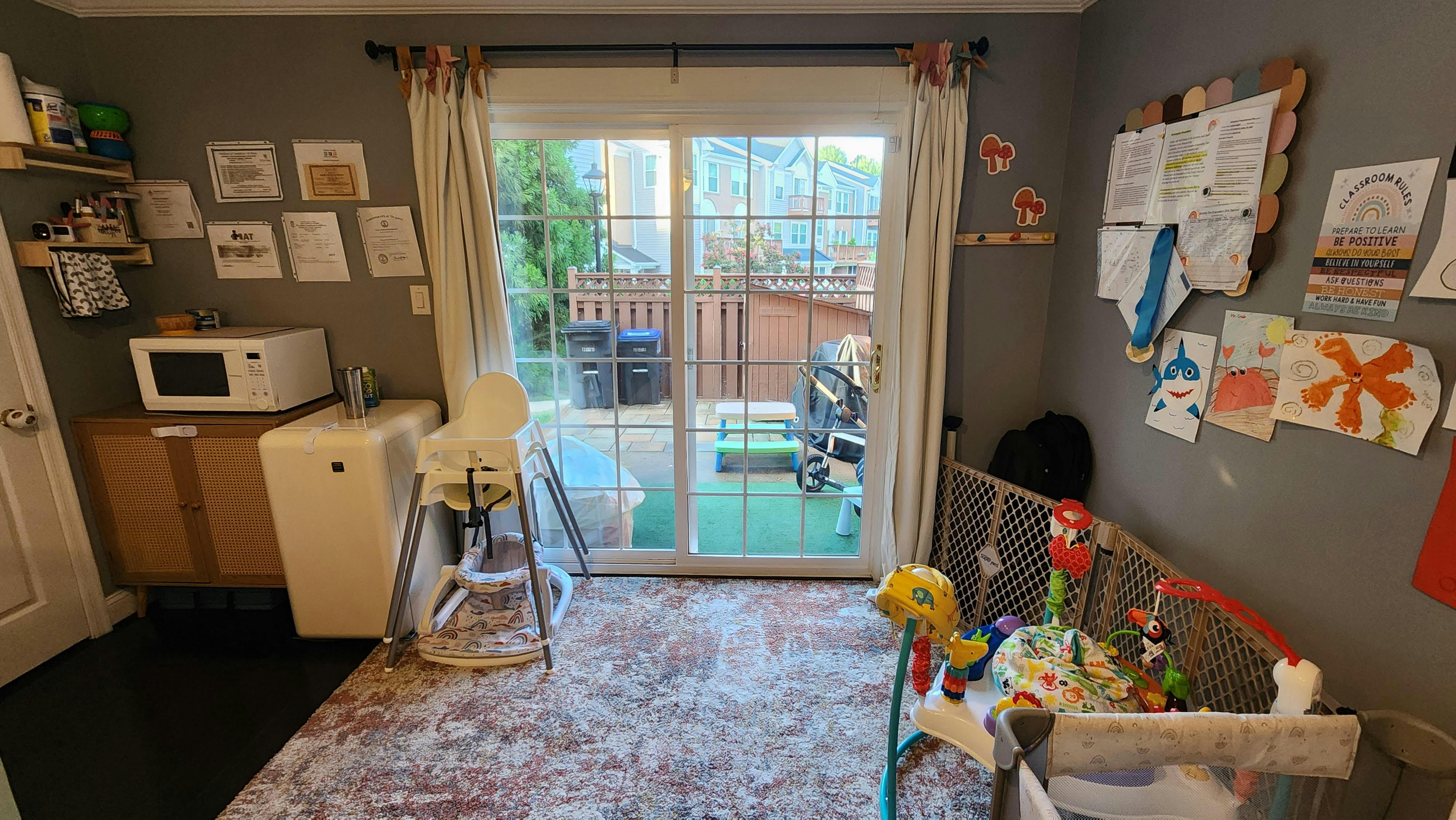 Room with a high chair, crib, and sliding glass door to a patio
