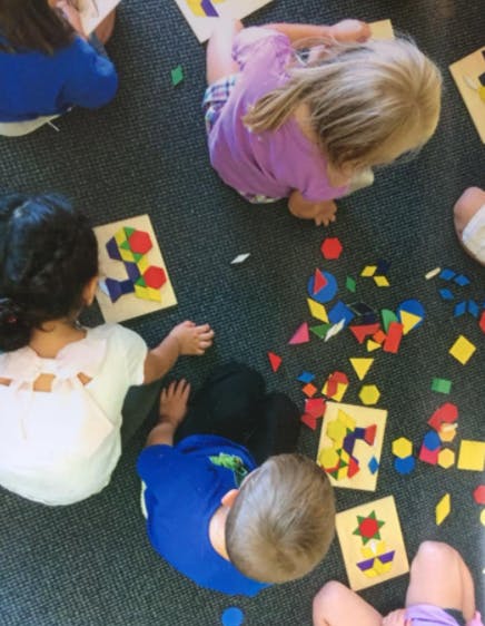 Children playing with colorful geometric shapes on the floor