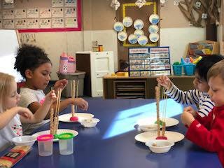 Children playing with toys at a table in a classroom