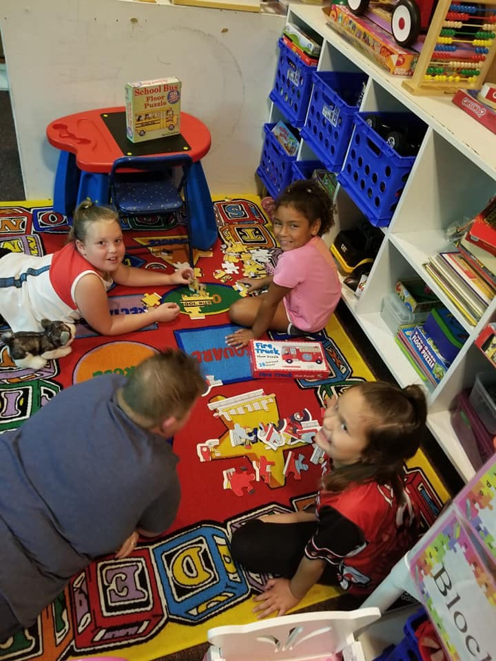 Four children playing with puzzles on a colorful rug