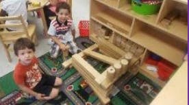Two children playing with wooden blocks on a rug