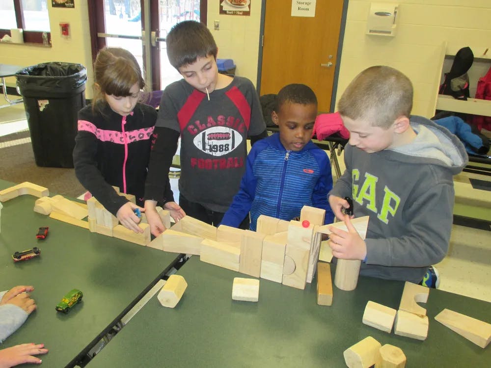 Four children building with wooden blocks on a table
