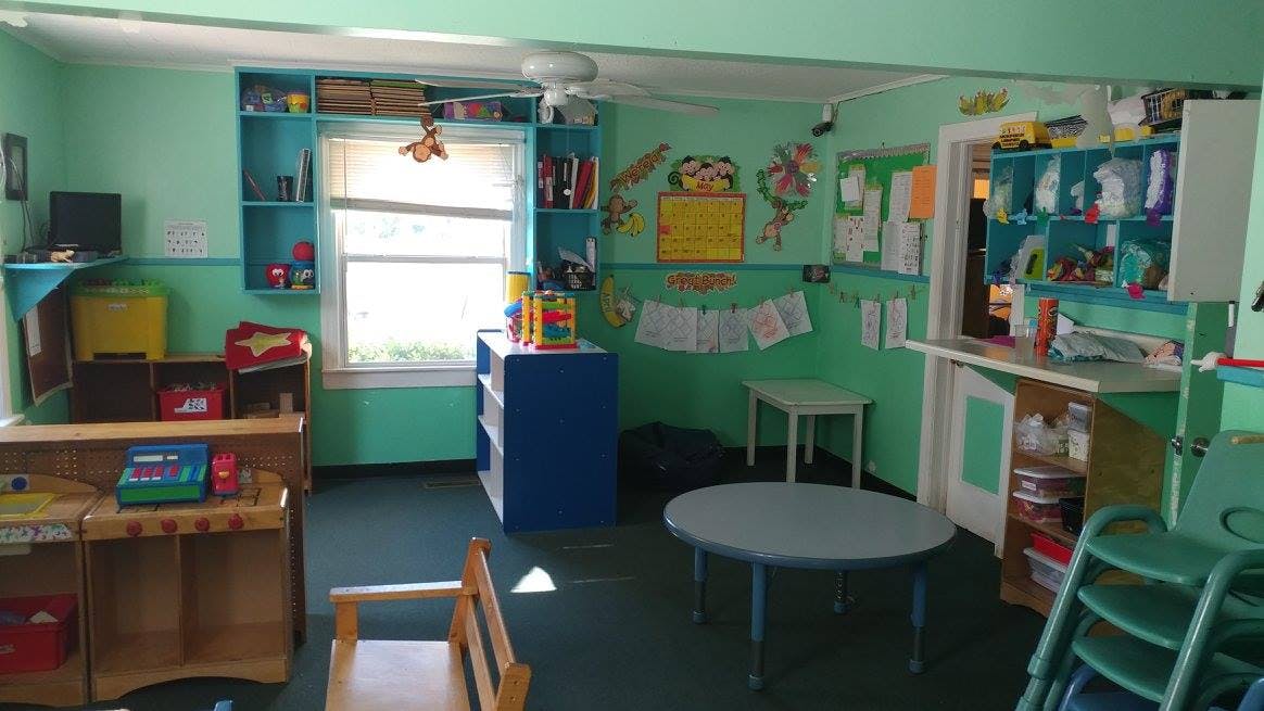 Classroom with green walls, shelves, tables, and chairs