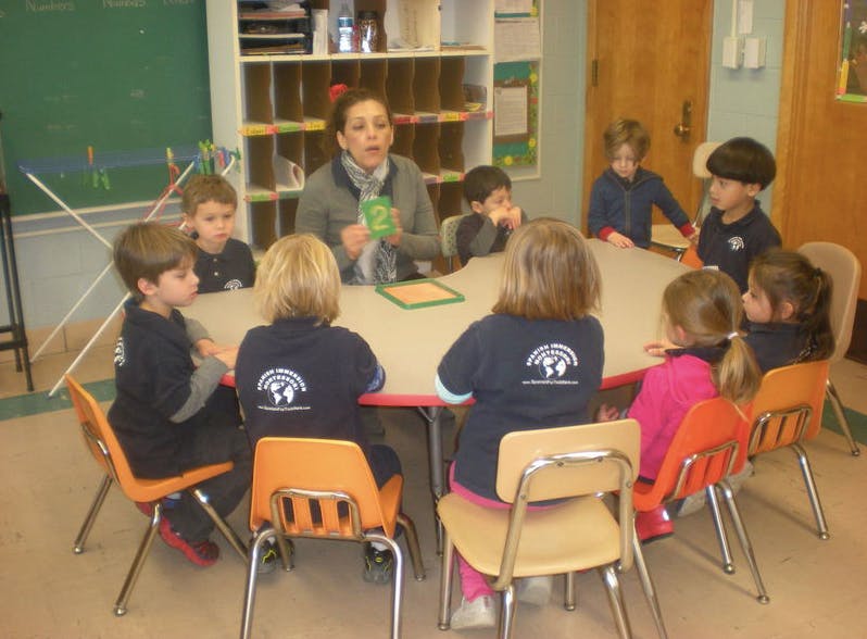 Adult and children sitting around a table in a classroom