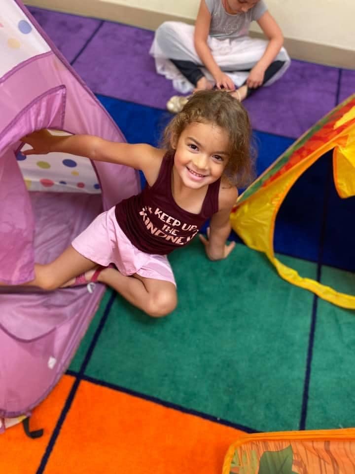 Child smiling while playing in a tent