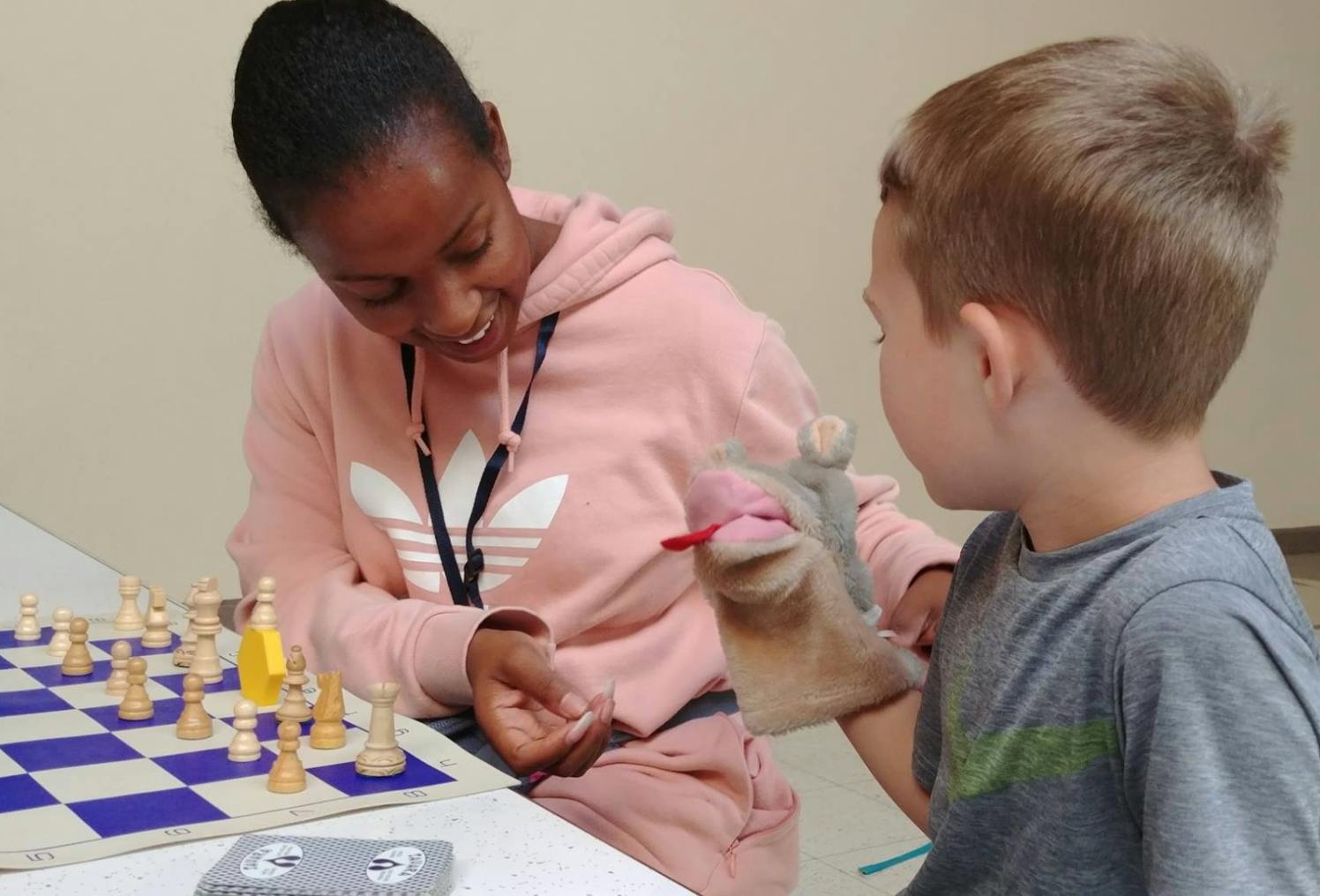 Person and child playing chess with a hand puppet