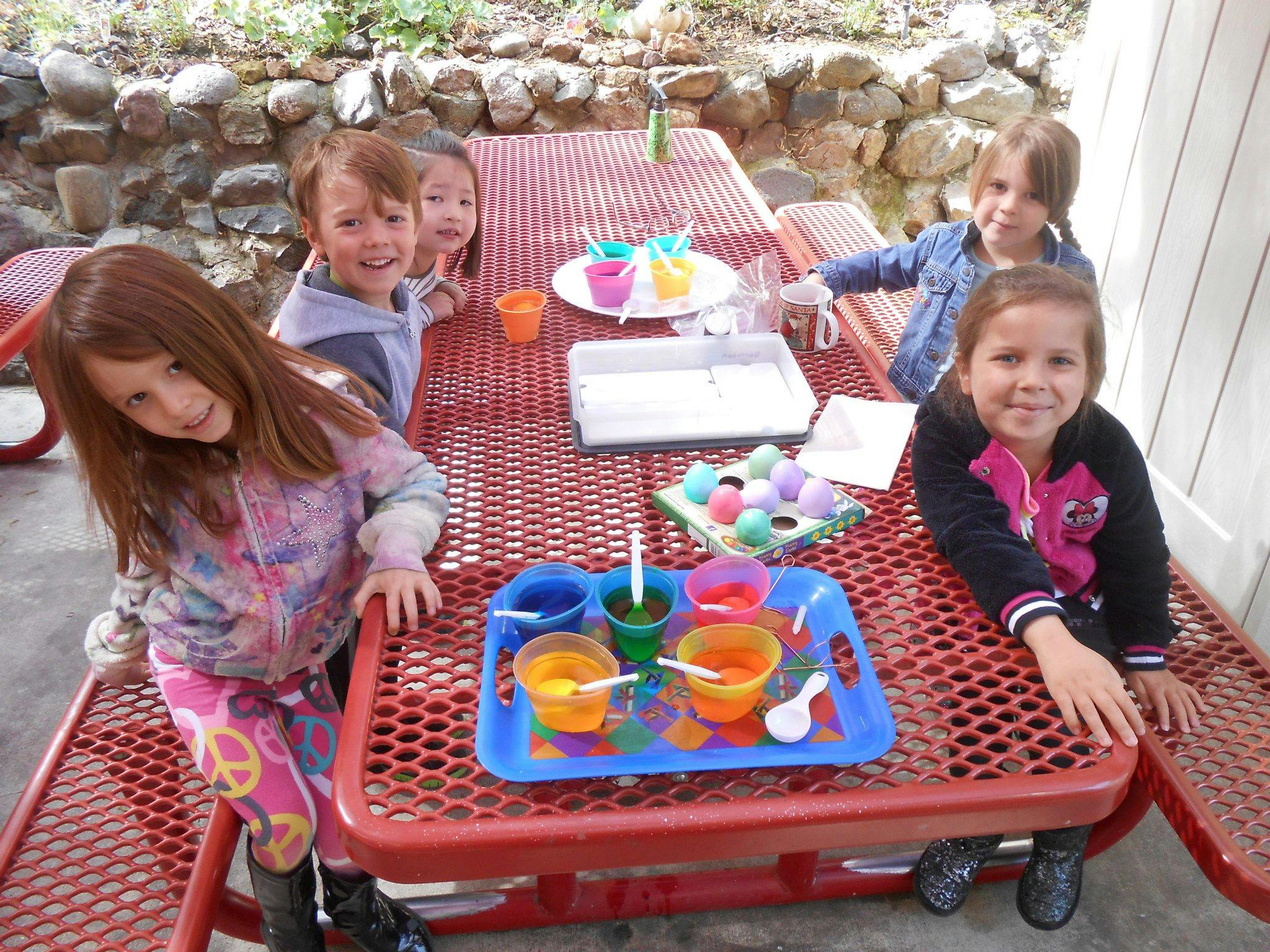 Children at a picnic table with egg dyeing supplies