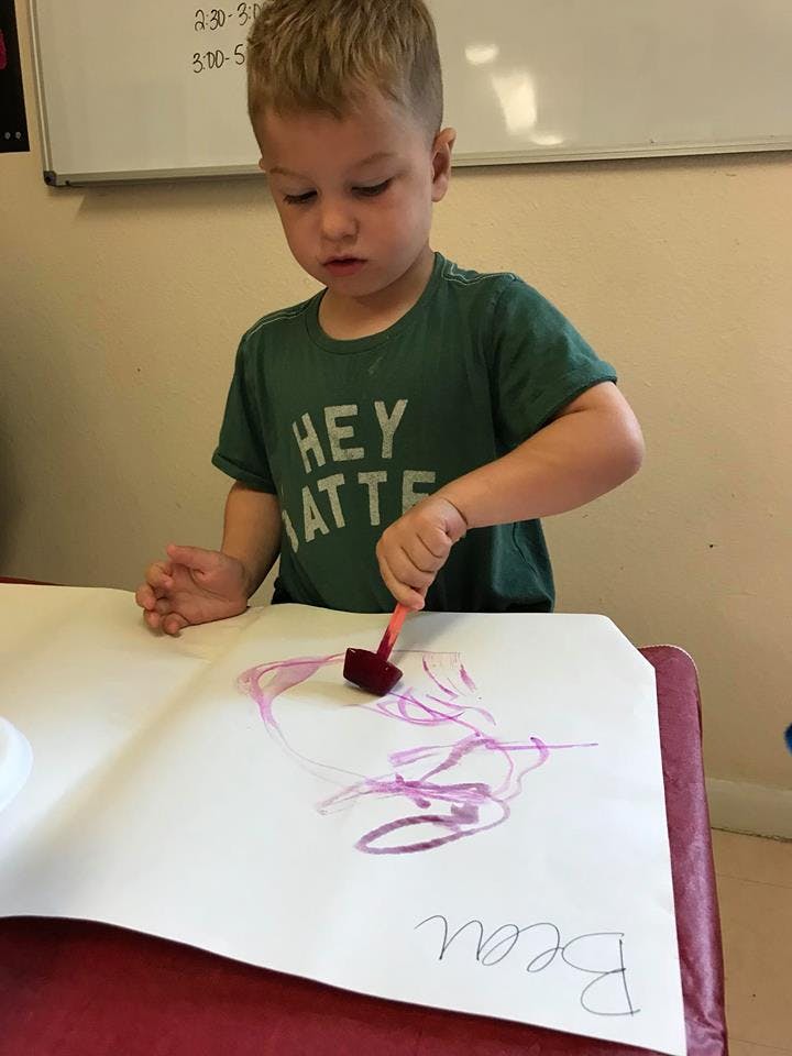 Child painting on paper with a sponge brush