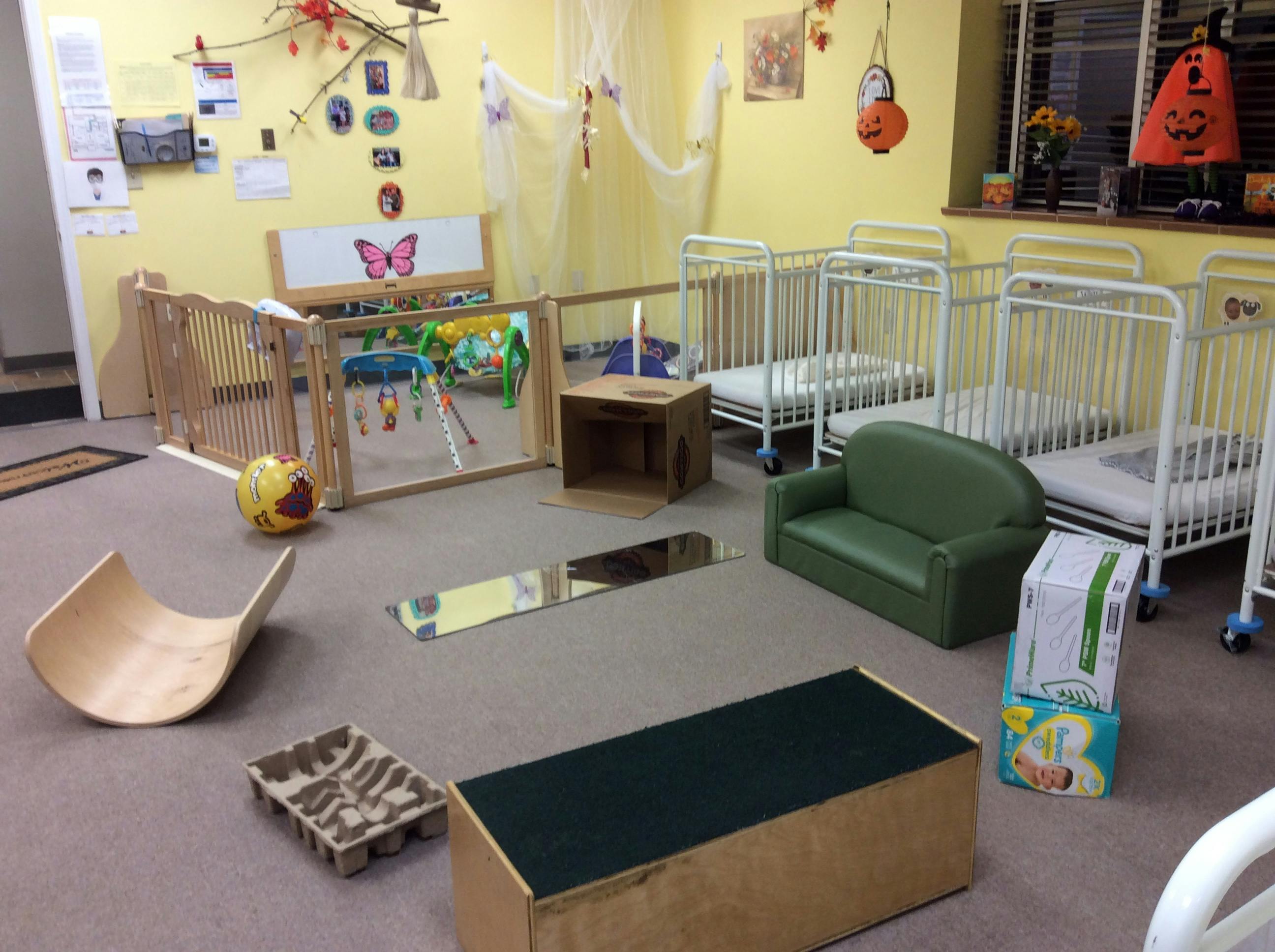 Daycare room with cribs, playpen, and various toys