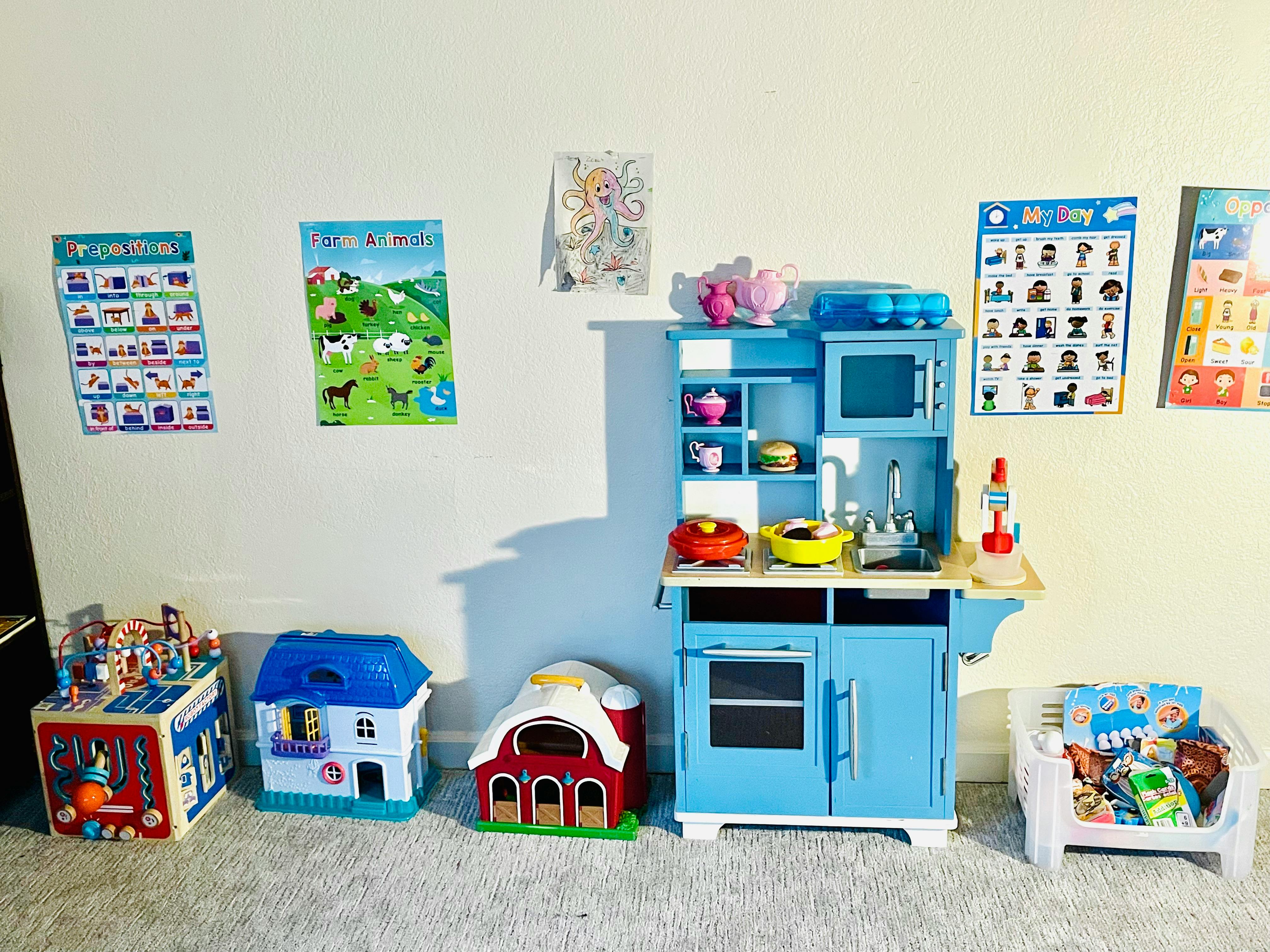 Children's play kitchen with toy houses and posters on the wall