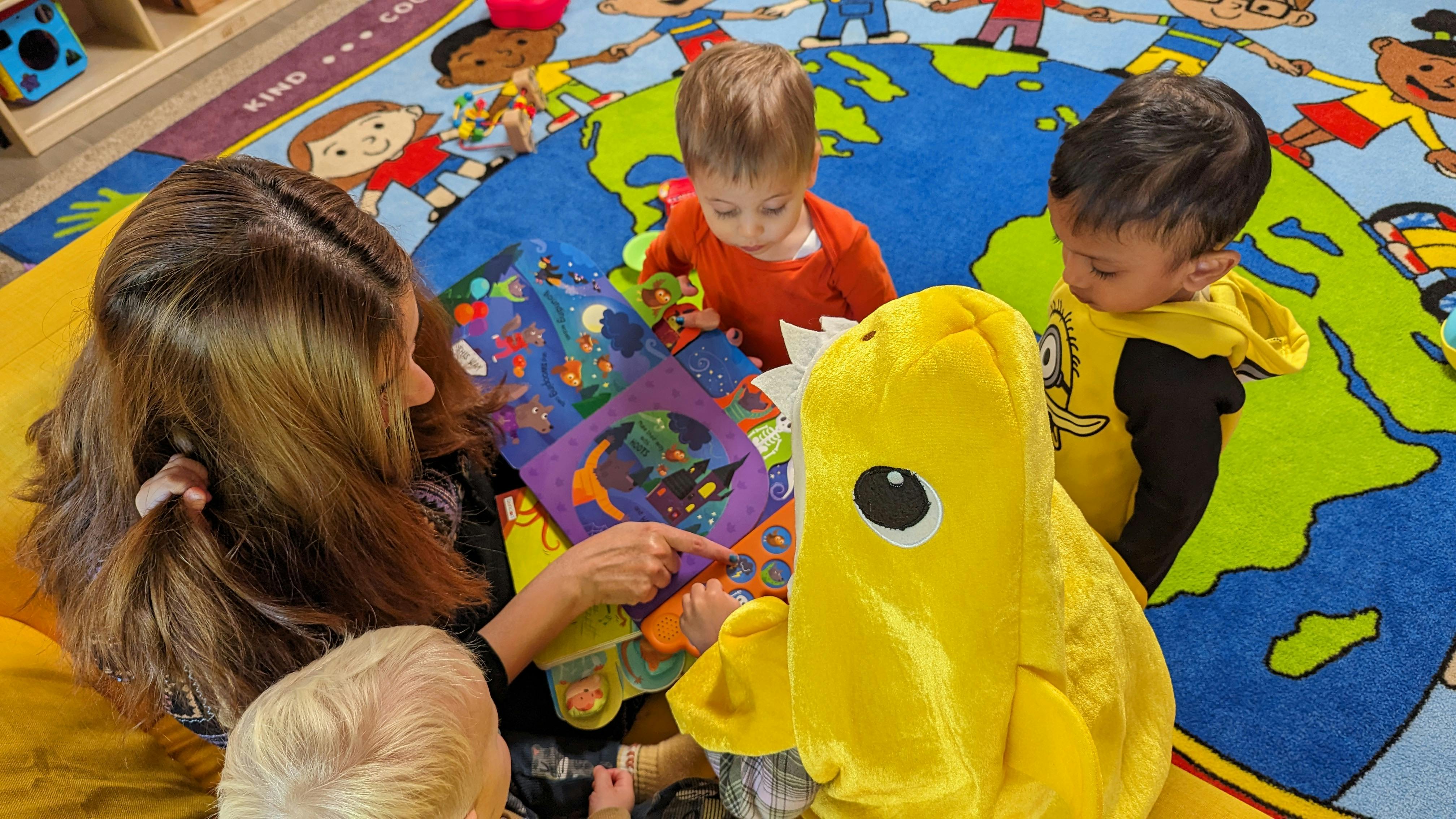 Person reading a book to children on a rug