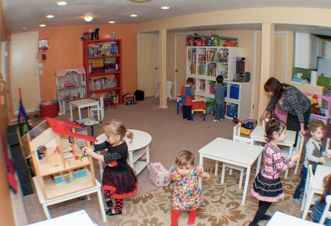 Children playing in a classroom with a person supervising
