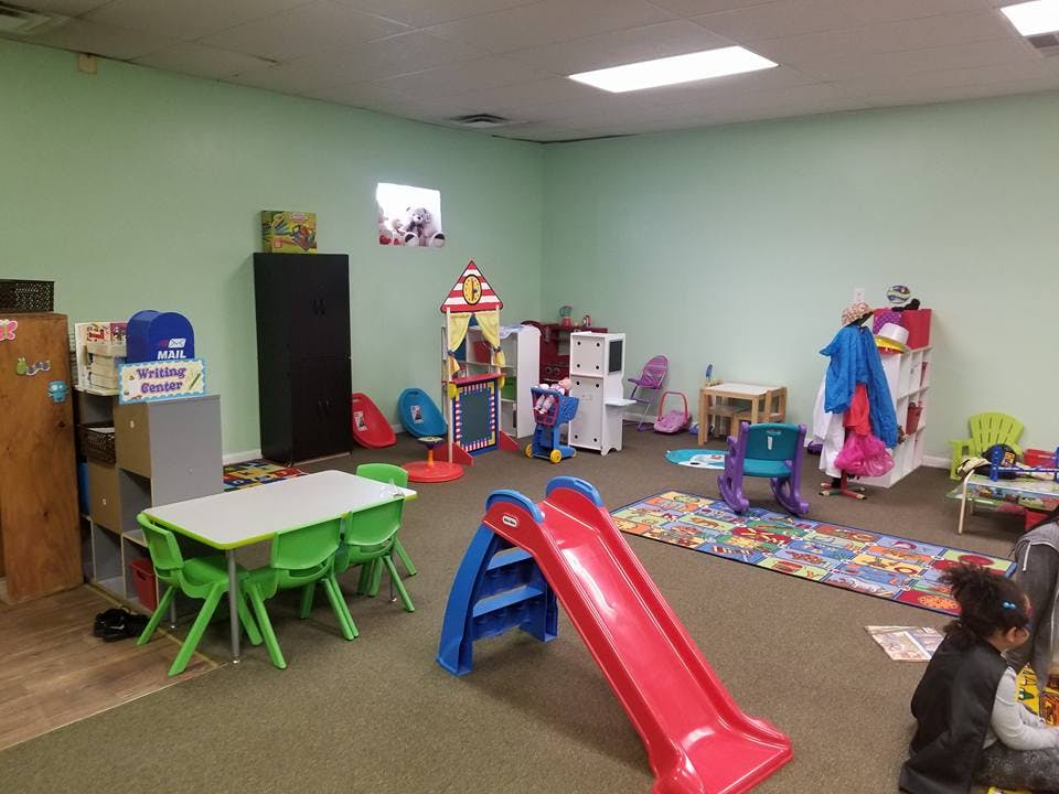 Playroom with a red slide, green table and chairs, and various toys
