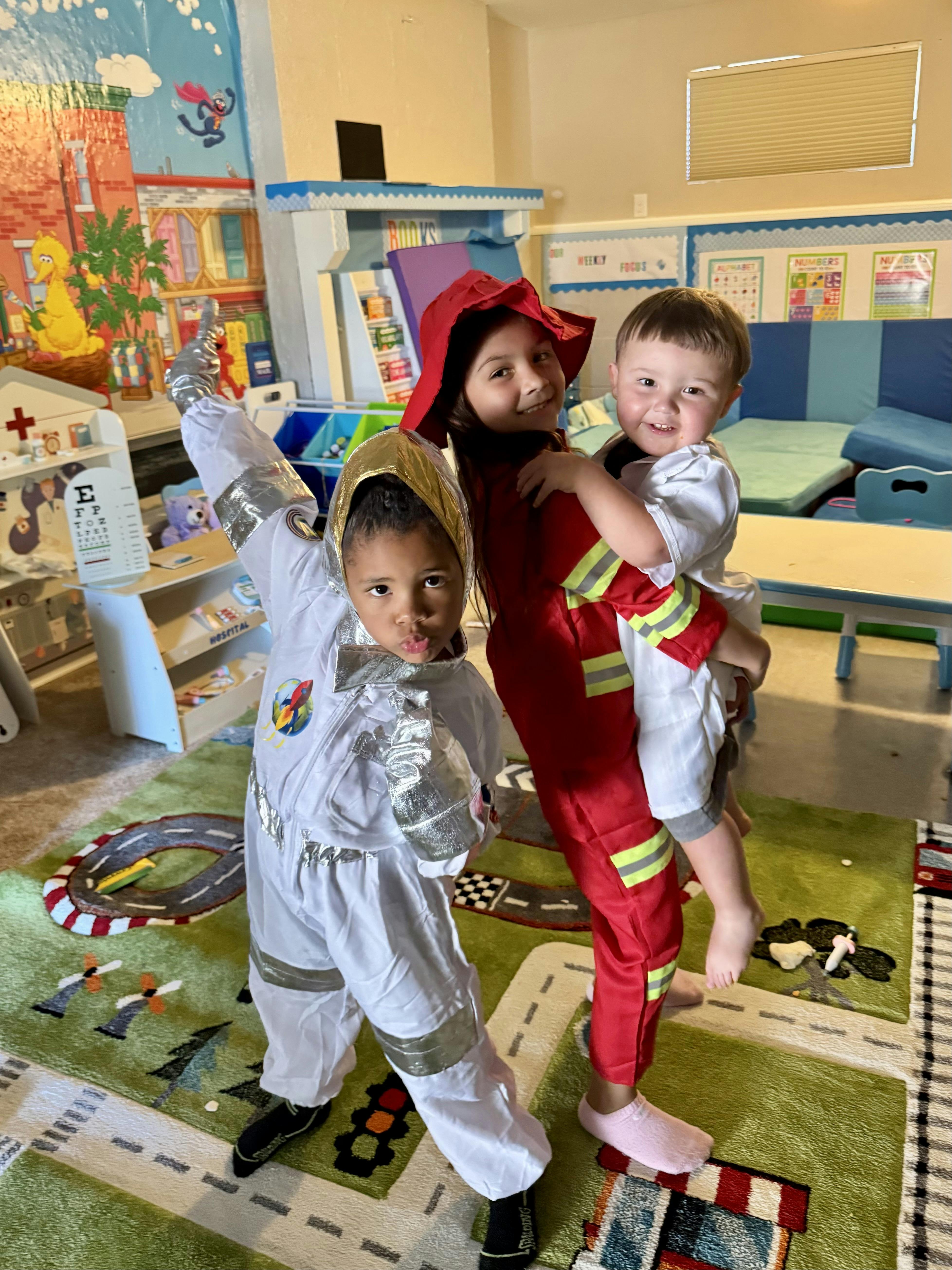 Three children in costumes playing in a classroom