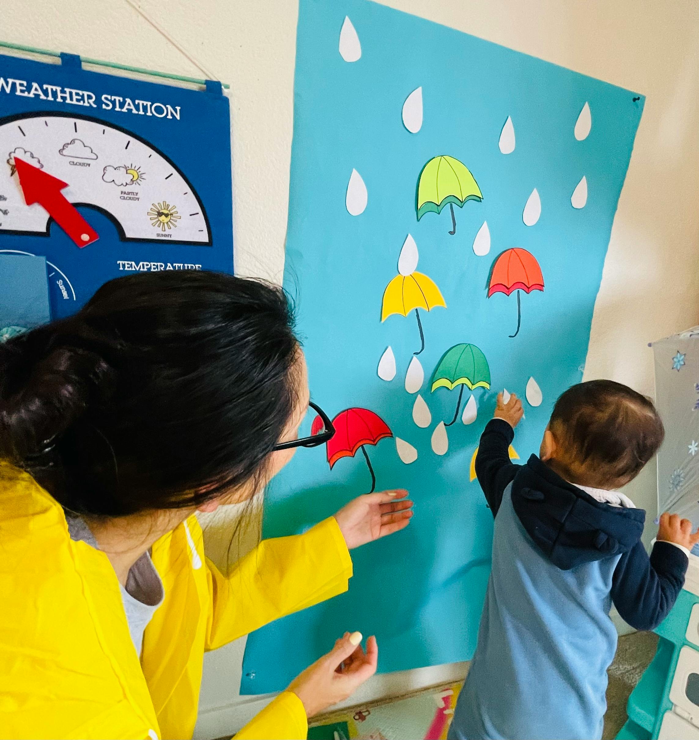 Person and child interacting with a weather-themed display