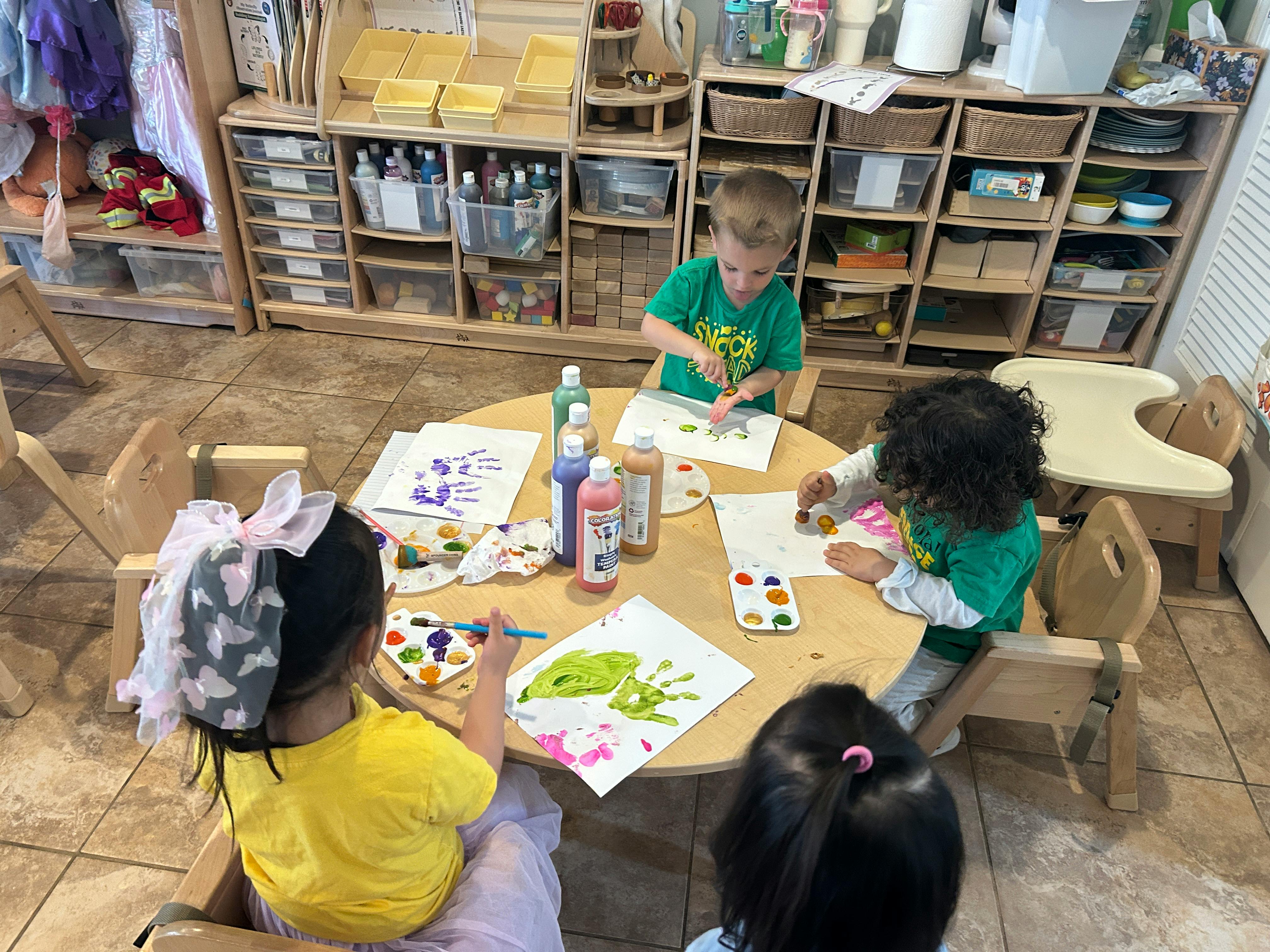Children painting at a round table in a classroom