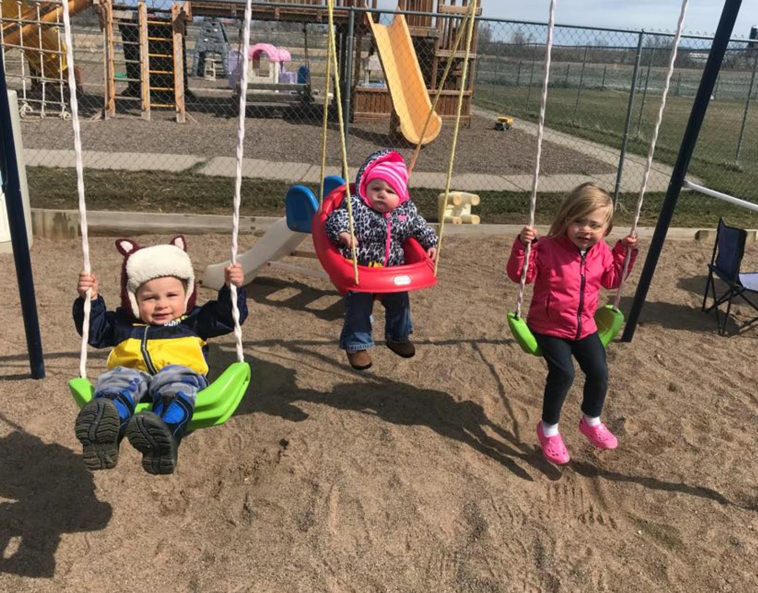 Three children on swings at a playground