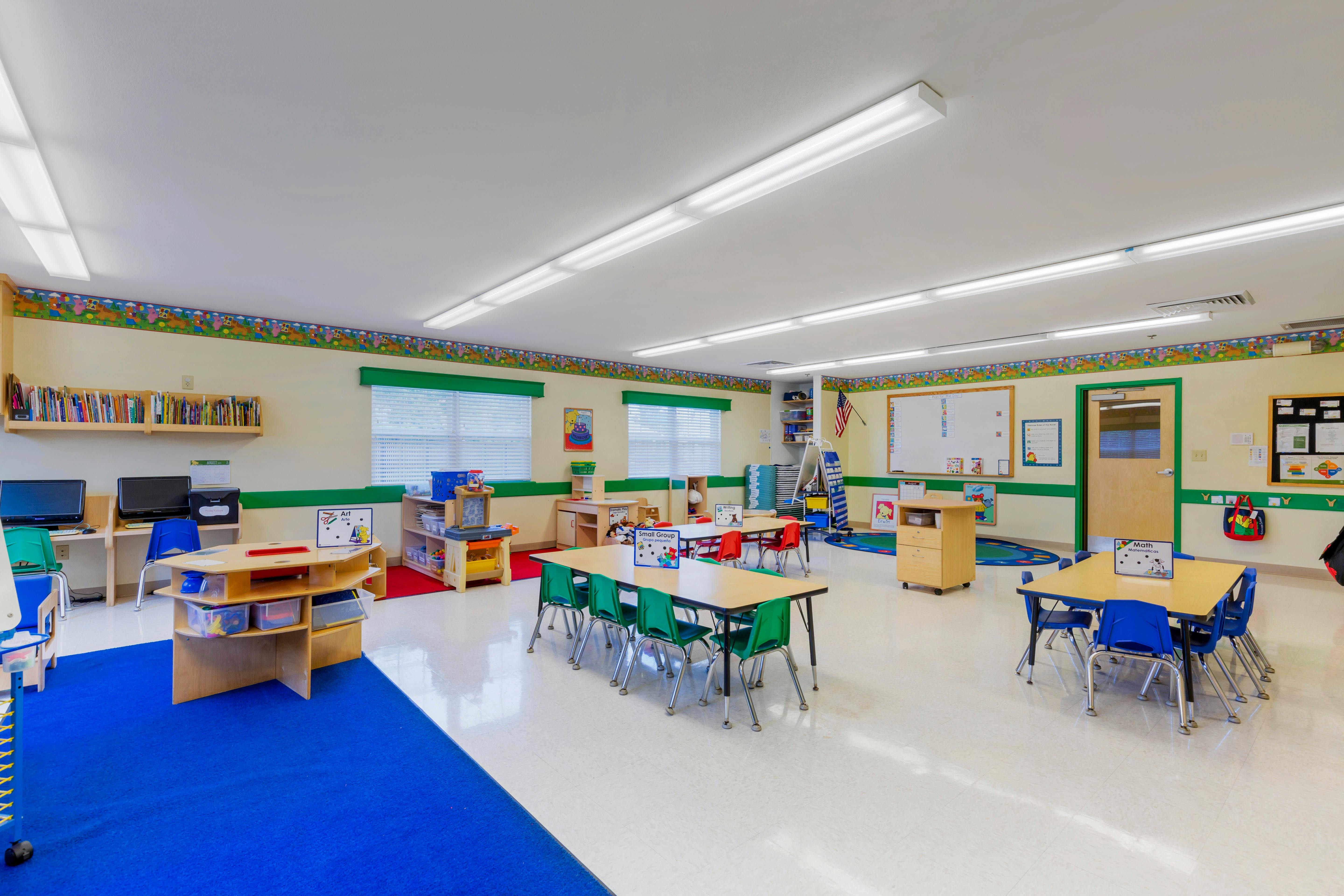 An empty early childhood classroom with multiple small tables and chairs