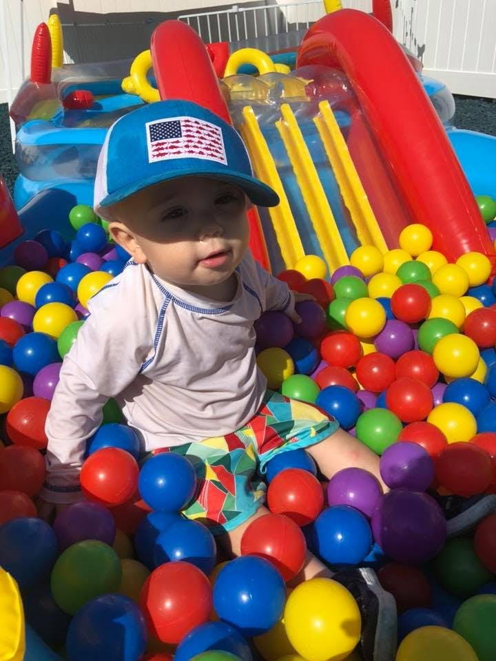Child in a ball pit wearing a hat with an American flag