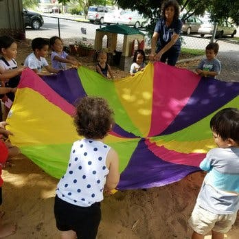 Adult and children playing with a colorful parachute