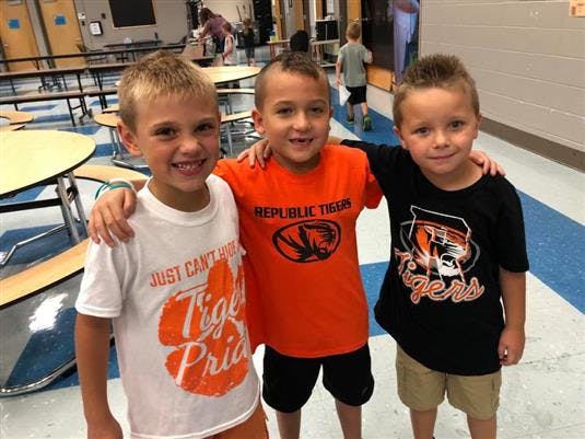 Three children standing with arms around each other