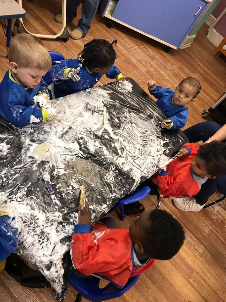 Children playing with shaving cream on a table