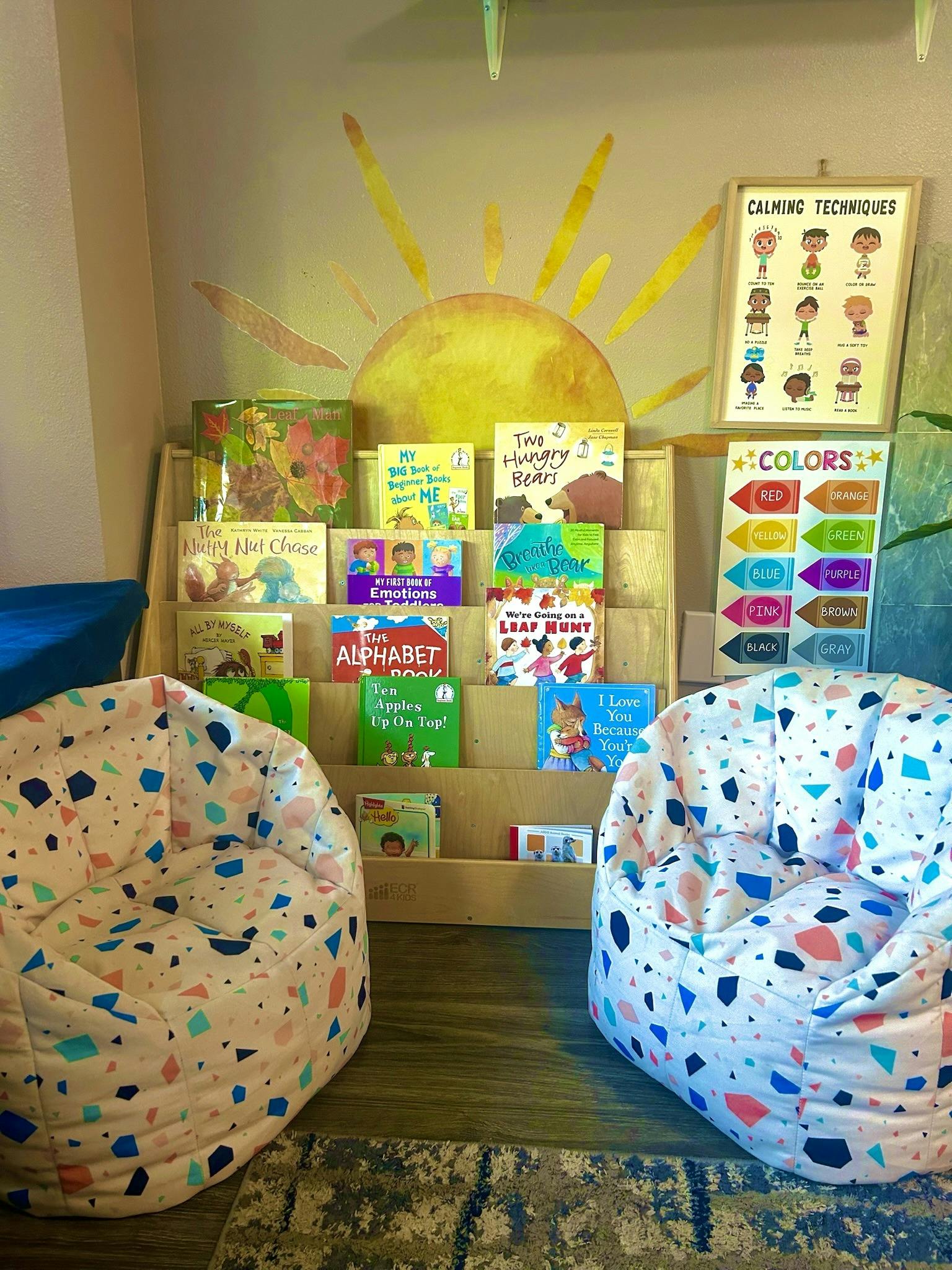 Two beanbag chairs in front of a bookshelf with children's books and posters