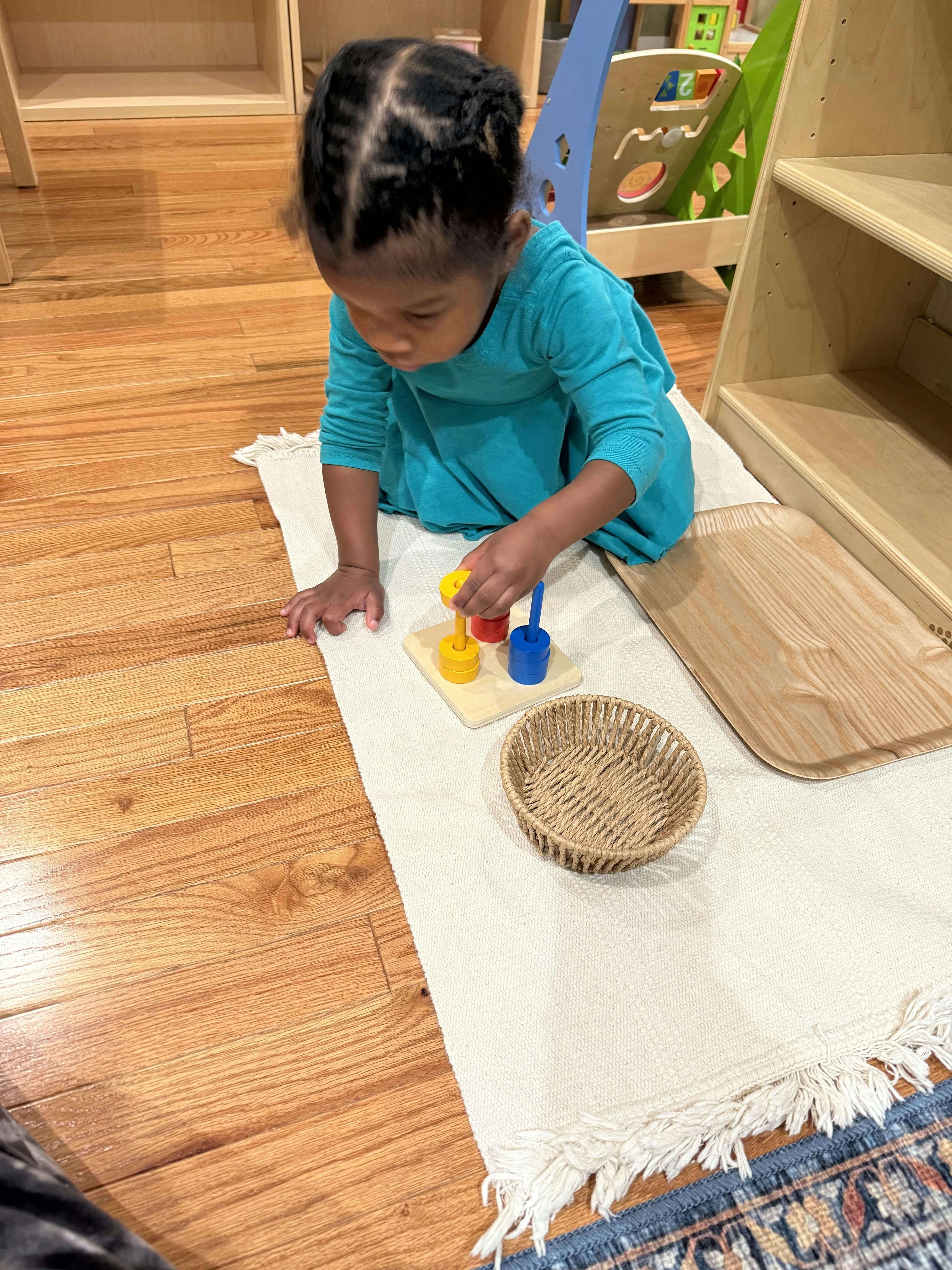Child playing with a colorful peg board toy on a white mat