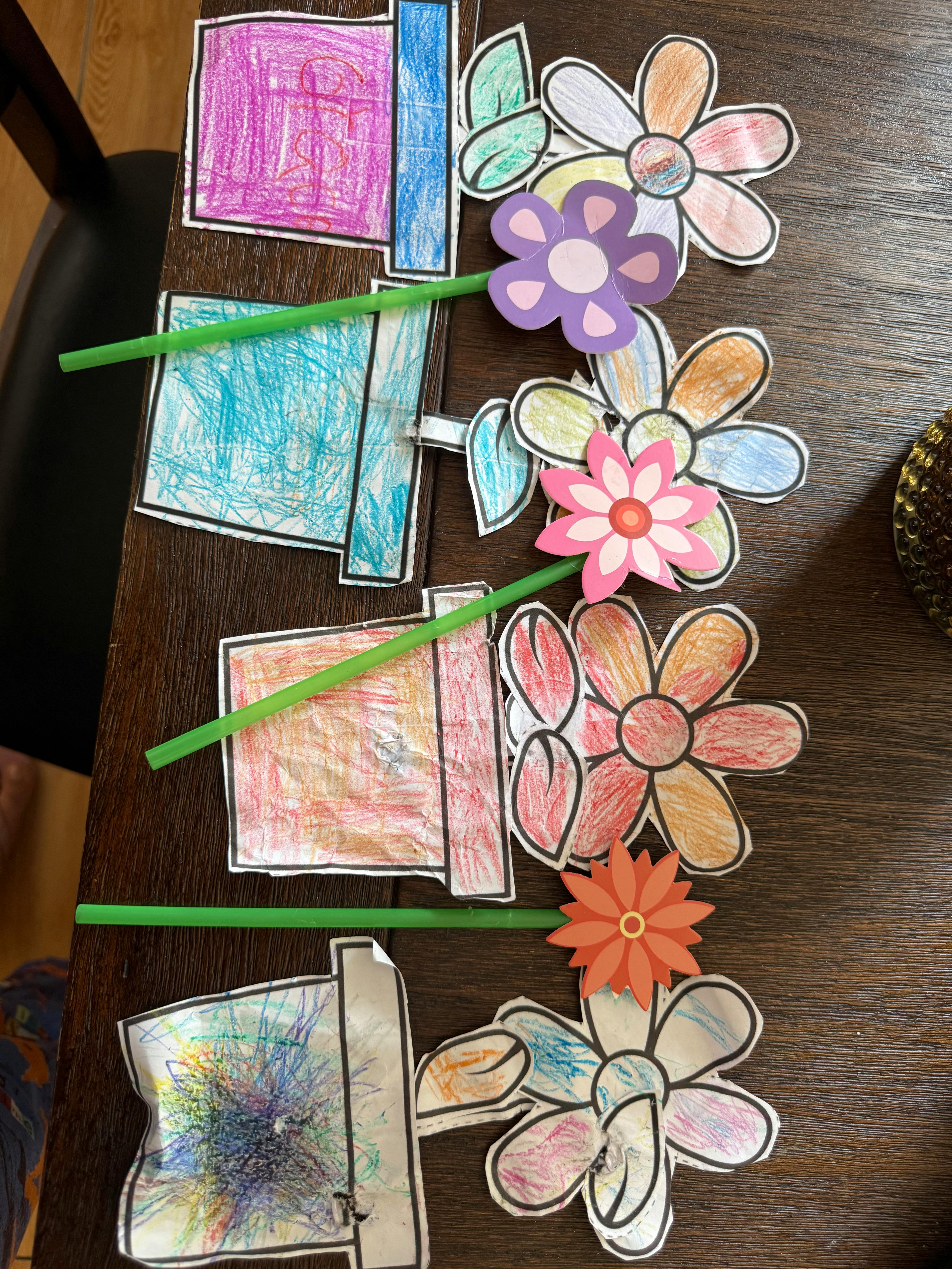 Paper flowers and pots made by a child with green straws as stems