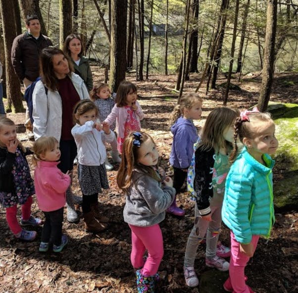 Adults and children walking through a wooded area