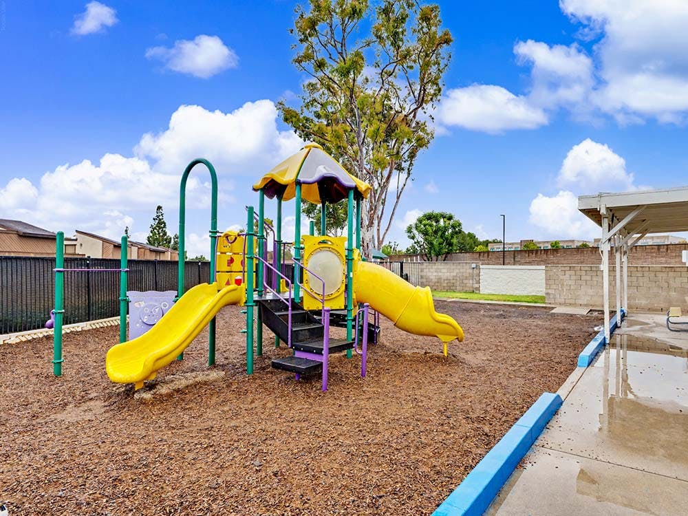 Colorful playground with two yellow slides on wood chips