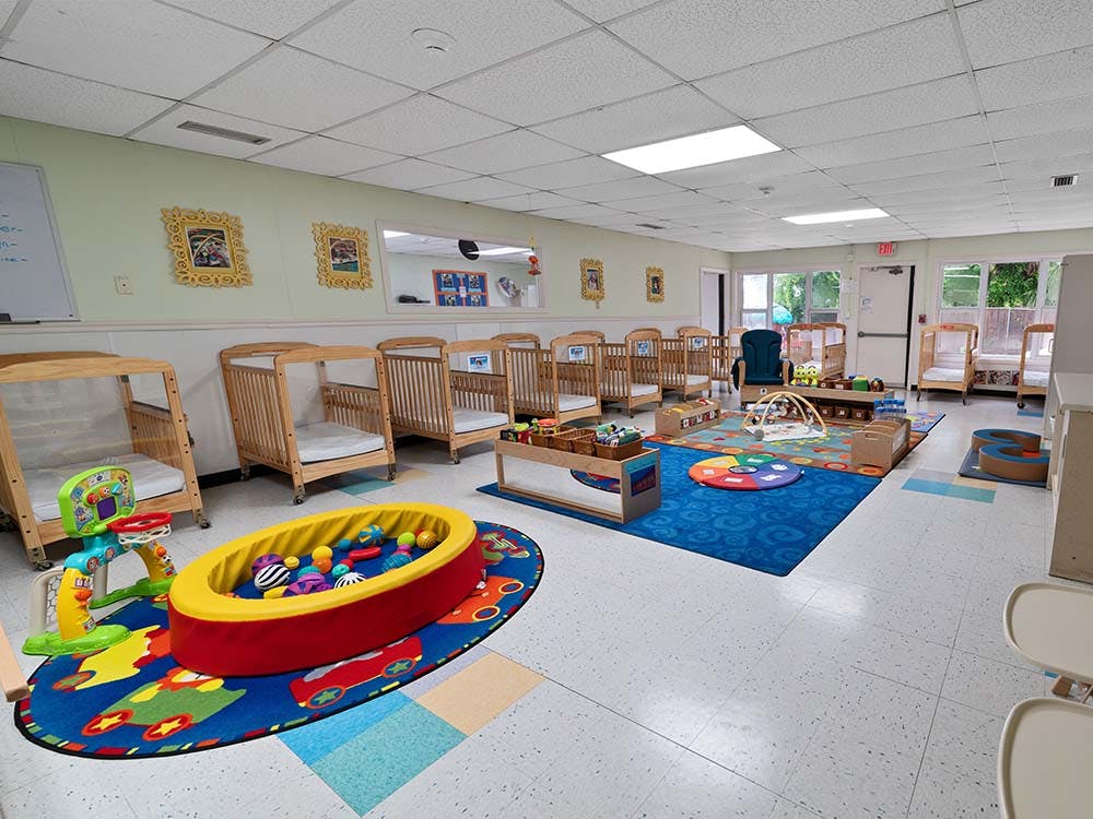 daycare room with multiple cribs, a ball pit, and play mats on the floor