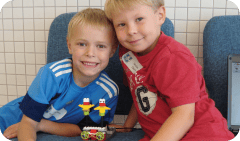 Two children sitting together, one in a blue shirt and one in a red shirt
