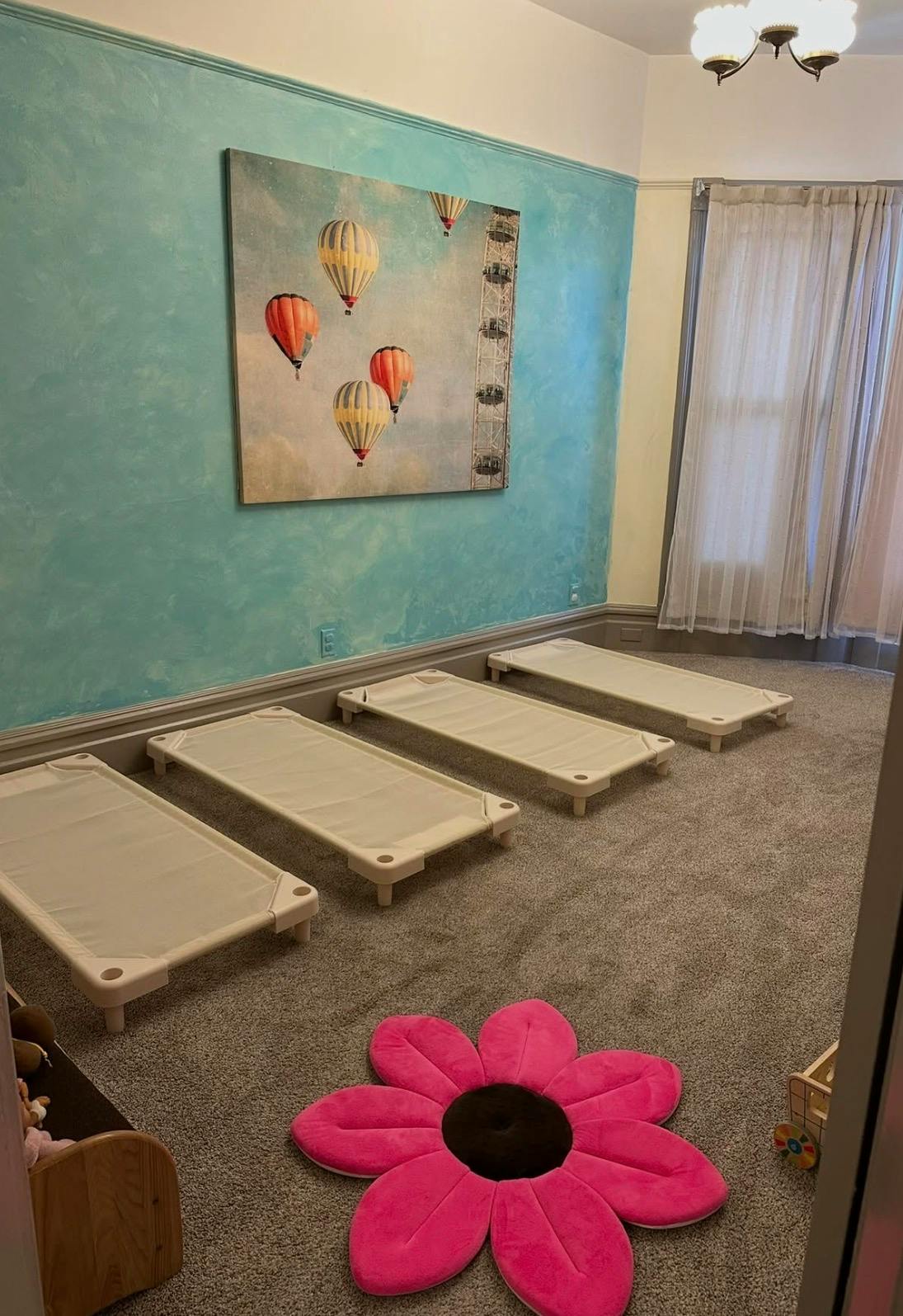 Three low cots arranged in a row in a room with a flower rug
