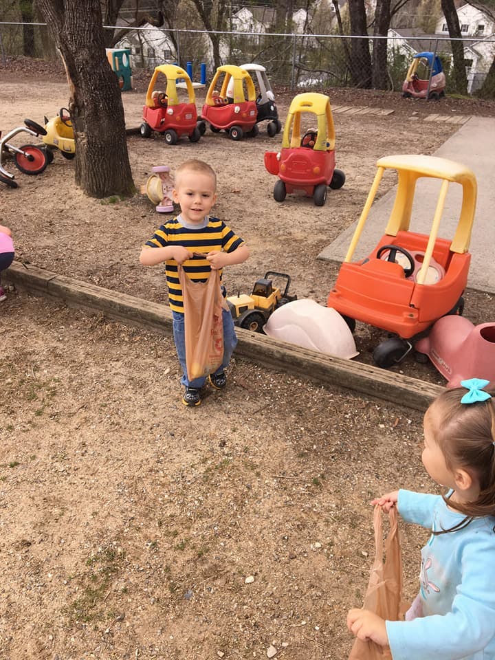 Child holding a bag on a playground with toy cars
