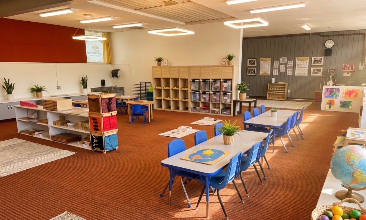 Spacious classroom with small tables and chairs and shelving for learning tools