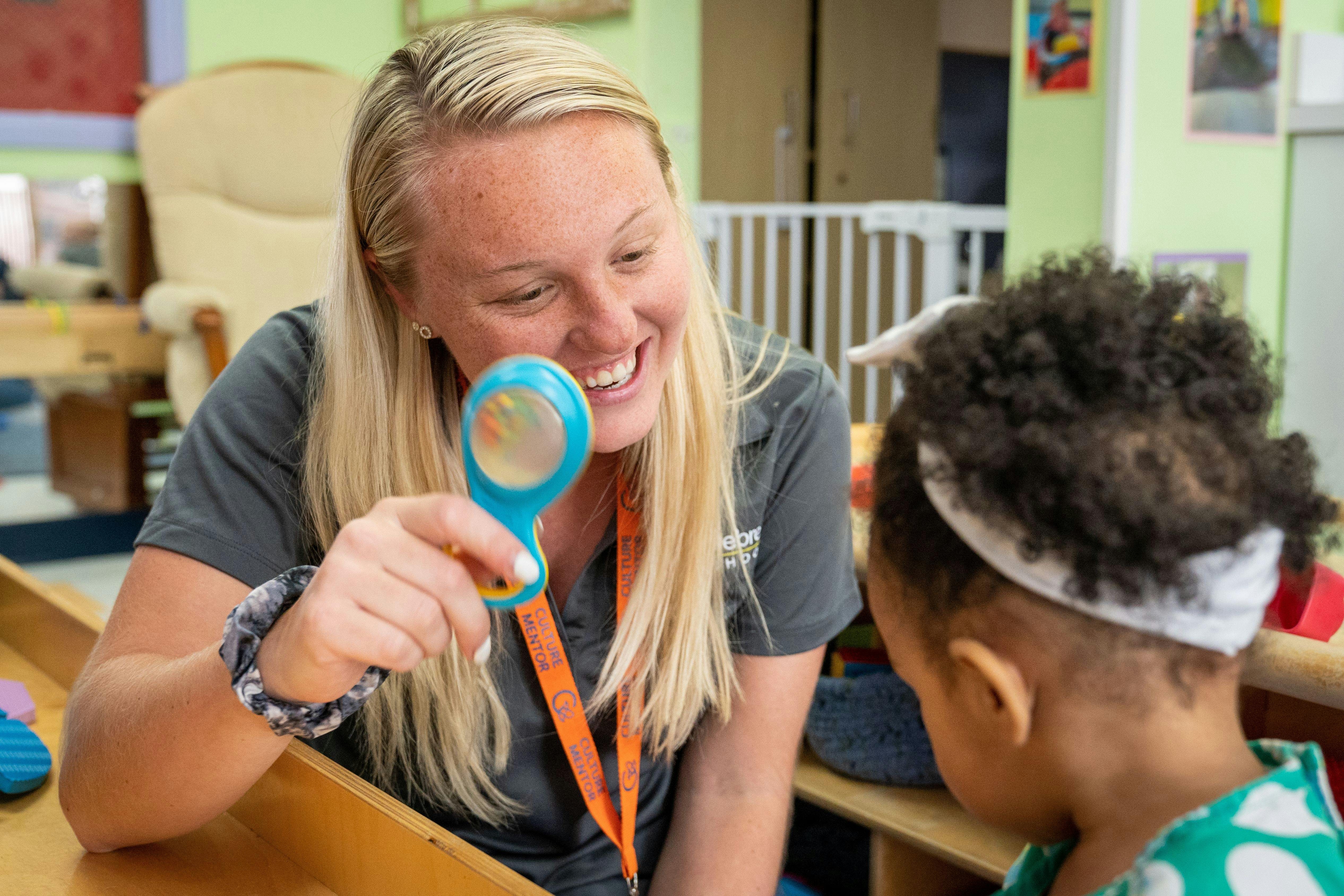 Person holding a magnifying glass toward a child