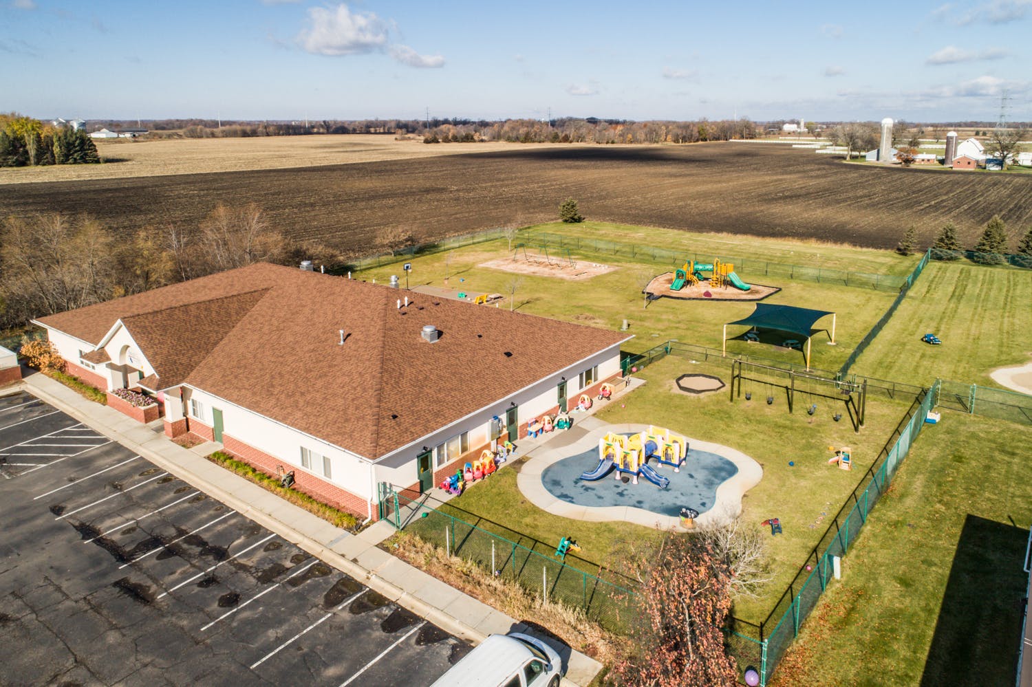 Aerial view of a building with a playground and parking lot