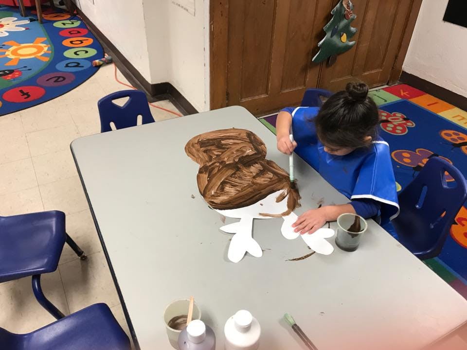 Child painting a paper cutout on a table