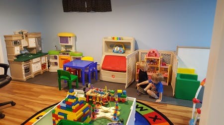Two children playing on the floor in a room with toys