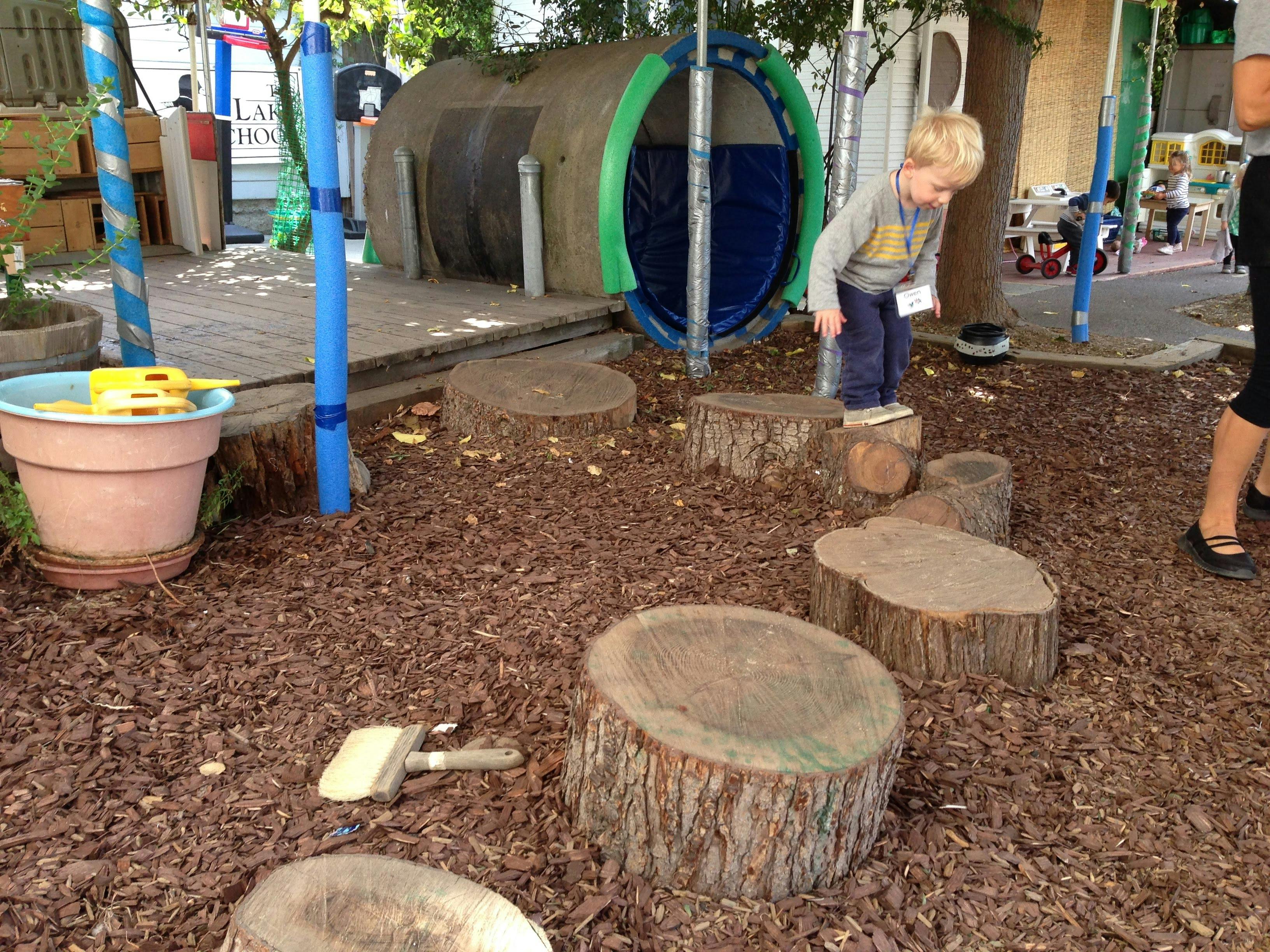 Child stepping on tree stumps in a playground