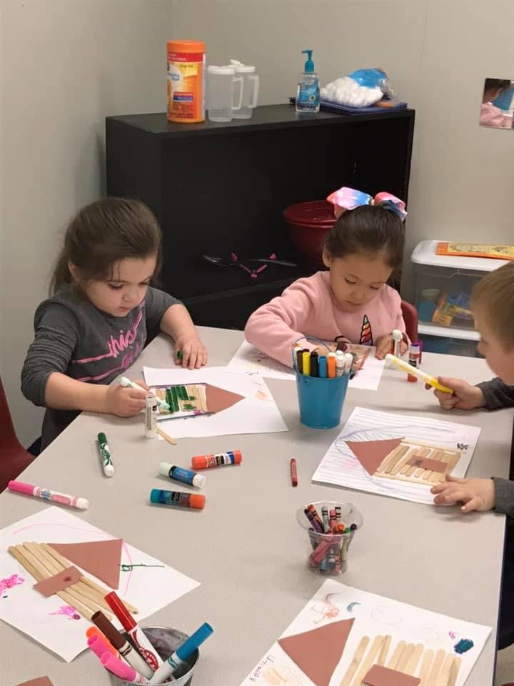 Children at a table doing crafts with craft supplies