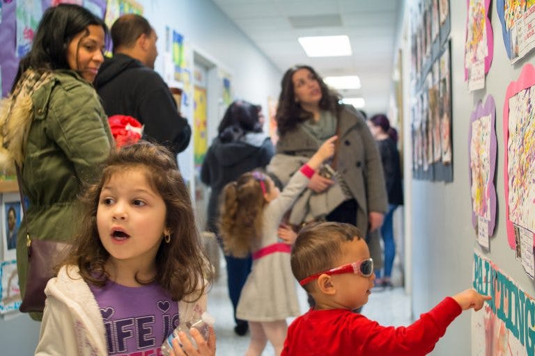 Children and adults looking at artwork displayed on a wall in a hallway