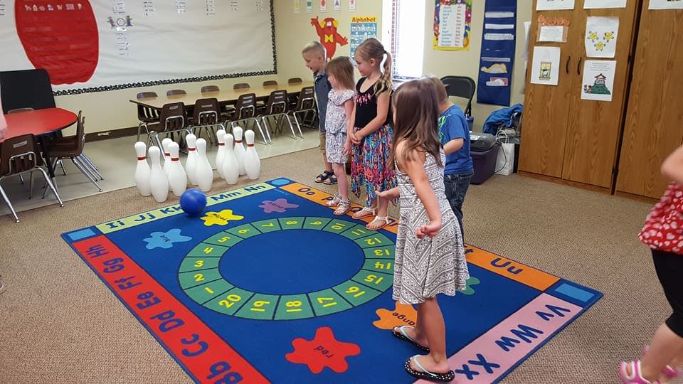 Children playing bowling in a classroom