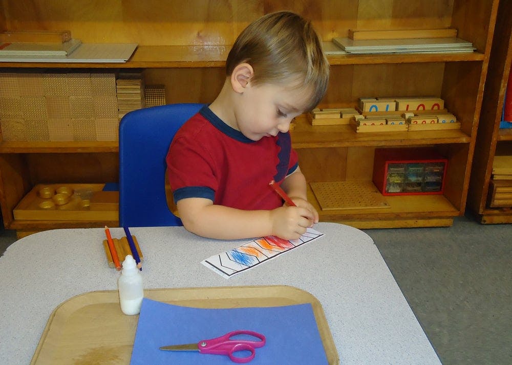 Child coloring at a table in a classroom
