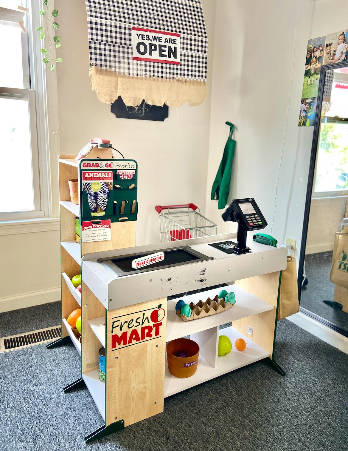 Play grocery store setup with "Fresh Mart" sign and "Yes, we are open" banner