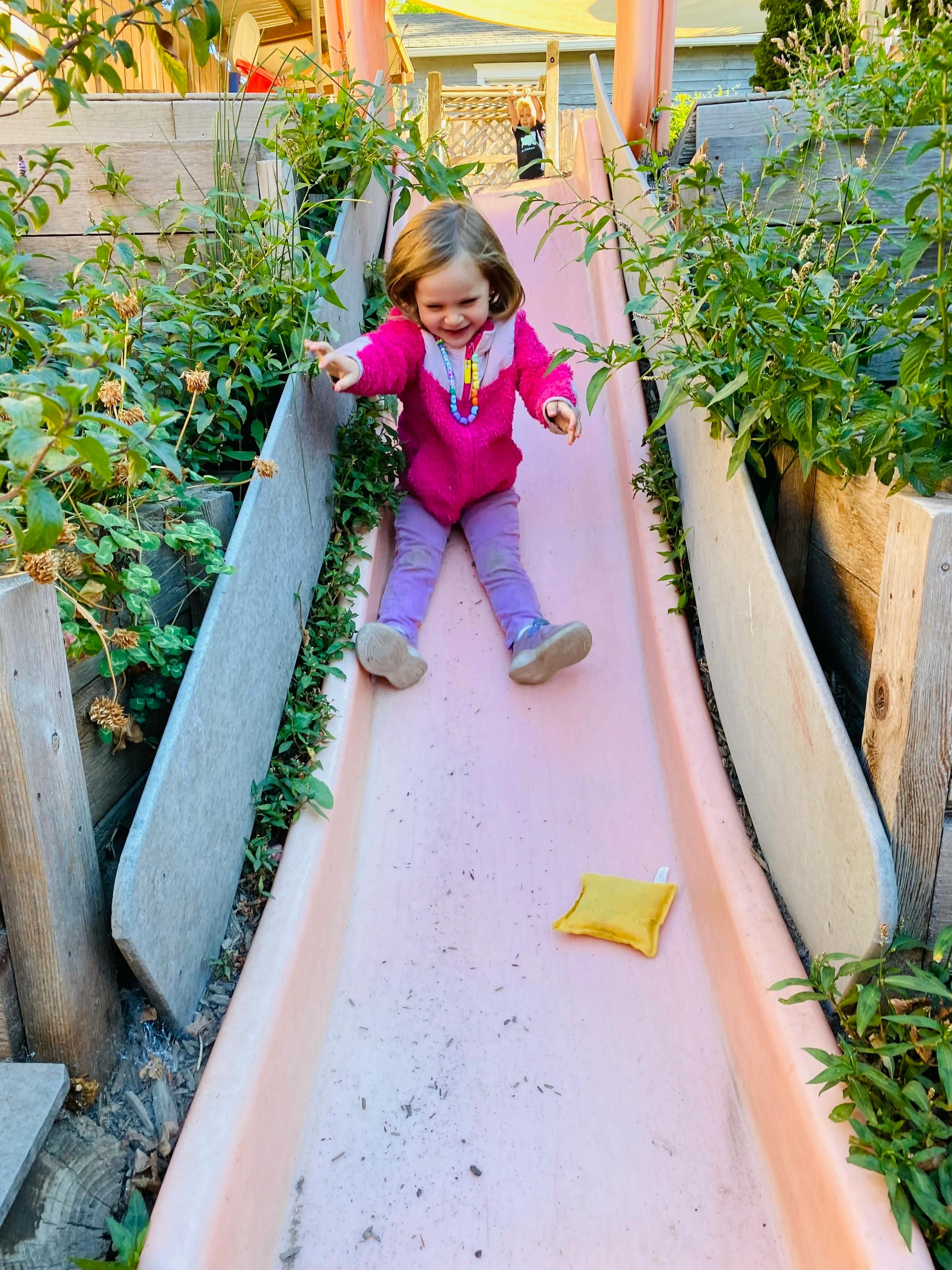 Child on a playground slide with another child in background